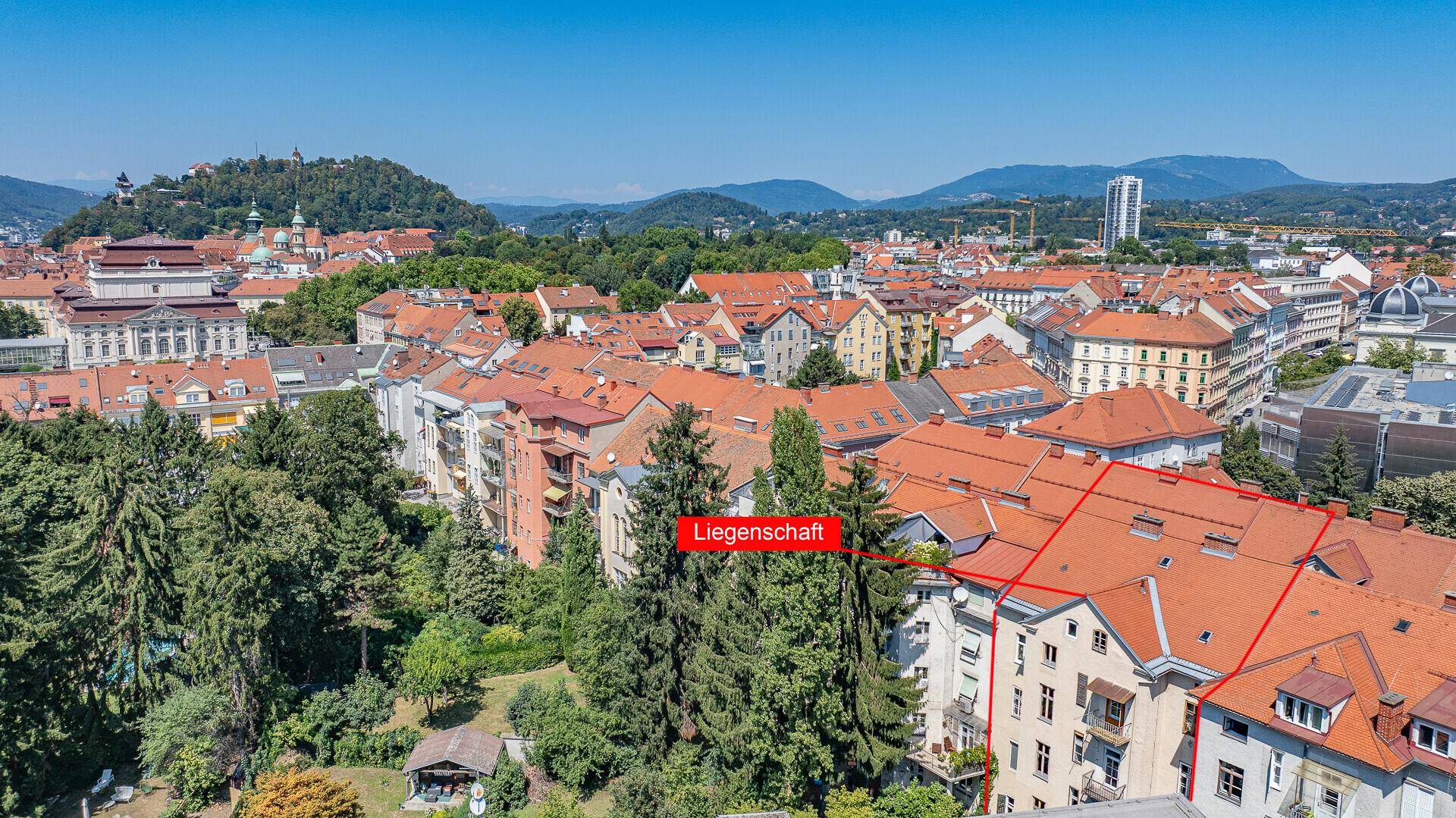 Panoramablick auf die Liegenschaft und die umliegende Stadtlandschaft mit viel Grün und Bergen.