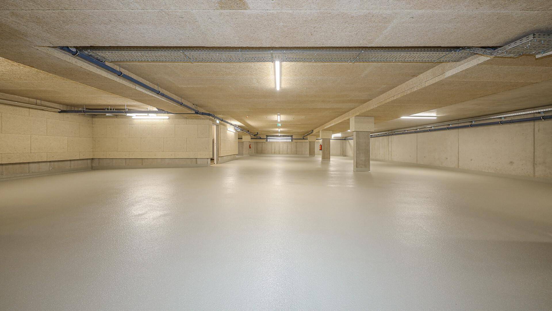 Geräumige Tiefgarage mit glattem Boden und Beleuchtung, bietet ausreichend Stellplätze.