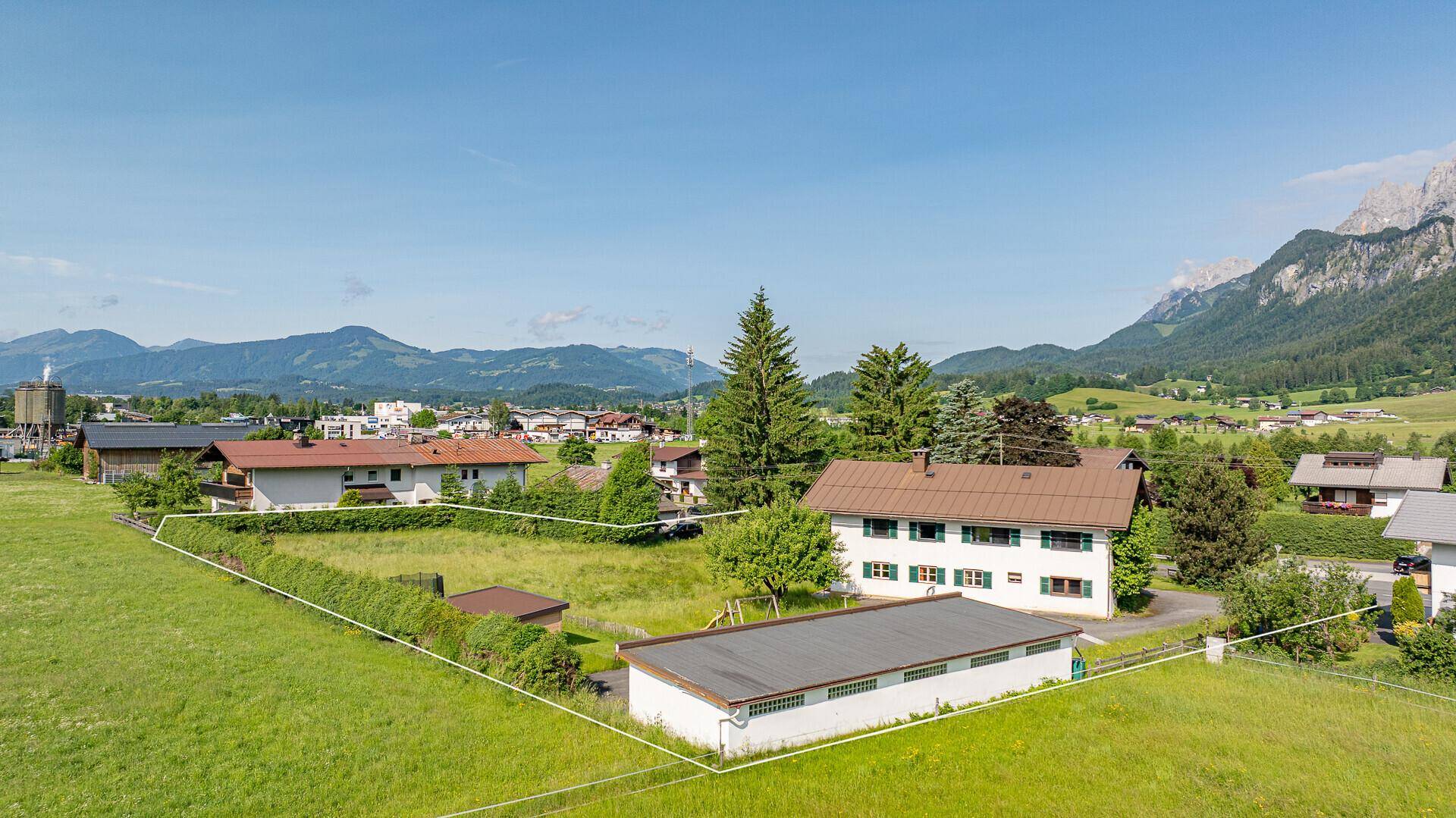 Blick auf das weitläufige Grundstück mit angrenzenden Gebäuden und der umliegenden Natur.