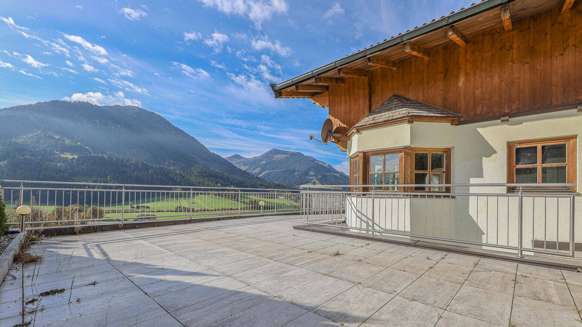 Sonnige Terrasse mit beeindruckendem Ausblick auf die majestätische Bergwelt und weite Felder.