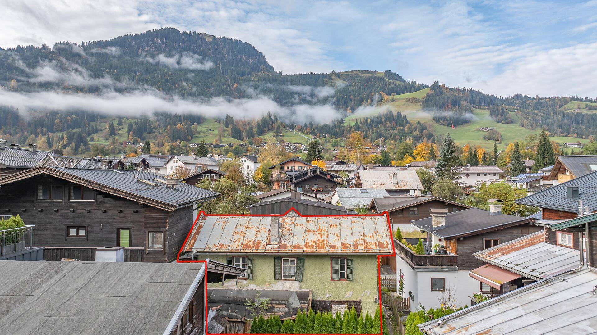 Luftaufnahme des alten Hauses mit roter Umrandung in einer Berglandschaft mit bewölktem Himmel.
