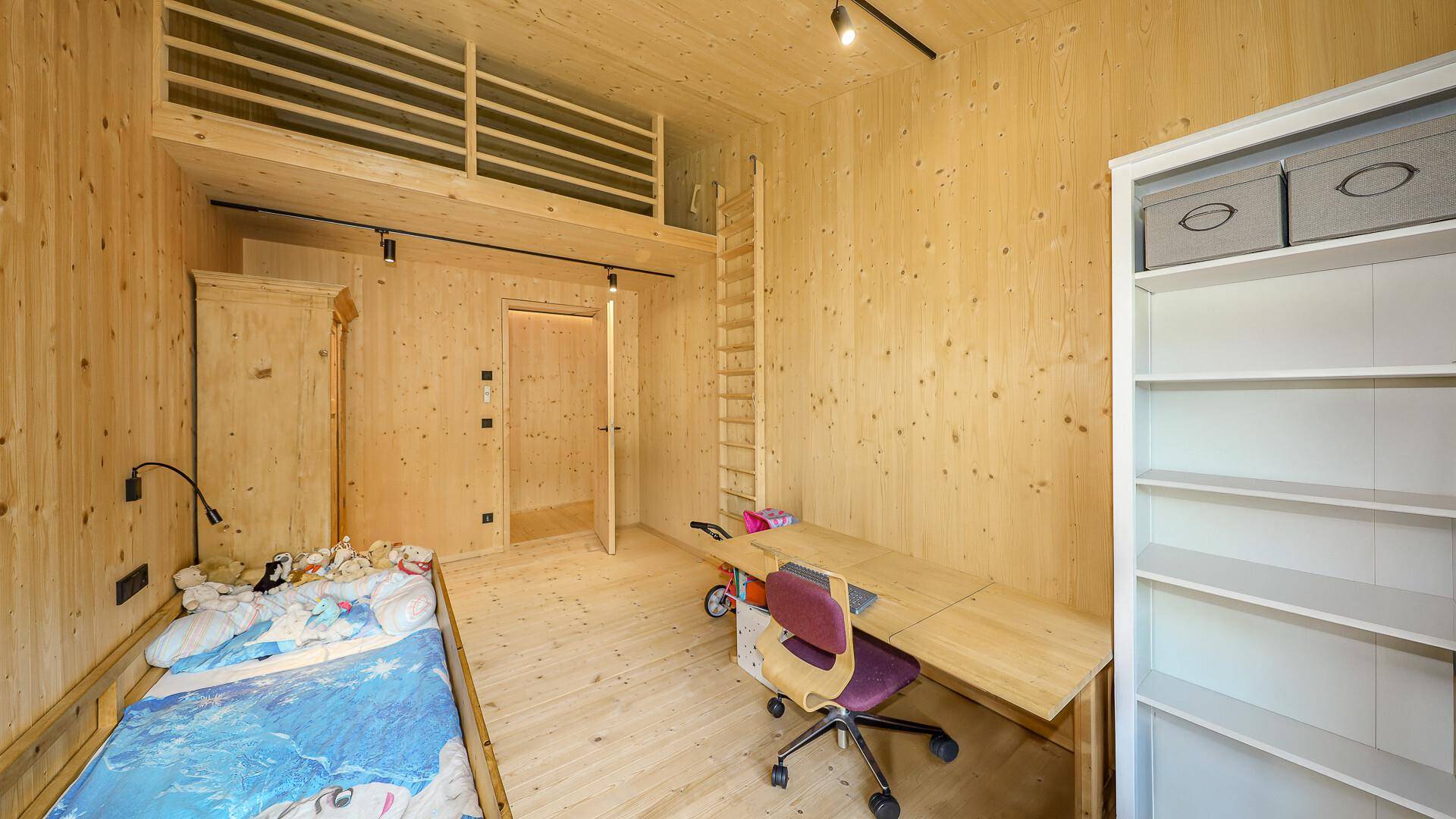 Helles Kinderzimmer mit Holzwänden, Schreibtisch und Hochbett, bietet viel Platz zum Spielen und Lernen.