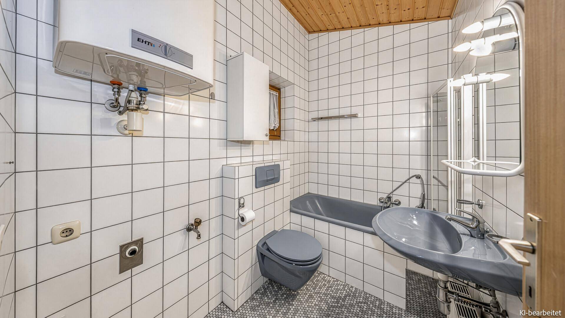 Helles Badezimmer mit weißen Fliesen, Badewanne, Toilette und Waschbecken.