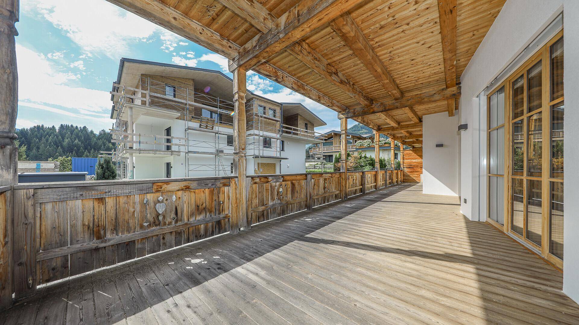 Langer Holzbalkon mit Blick auf benachbarte Gebäude und die Umgebung.