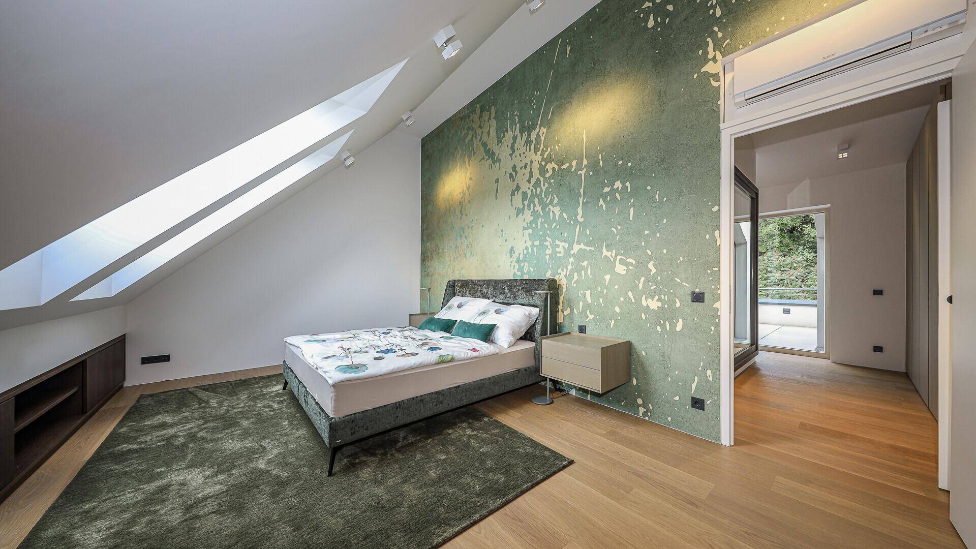 Modernes Schlafzimmer im Dachgeschoss mit auffälliger grüner Akzentwand und Holzboden.