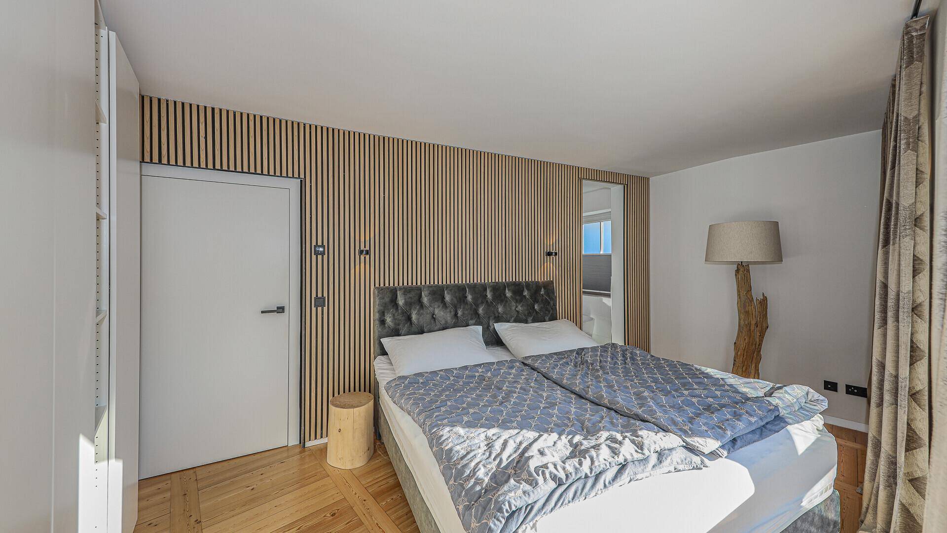 Gemütliches Schlafzimmer mit modernem Doppelbett und einer stilvollen Holzwand, die Wärme ausstrahlt.