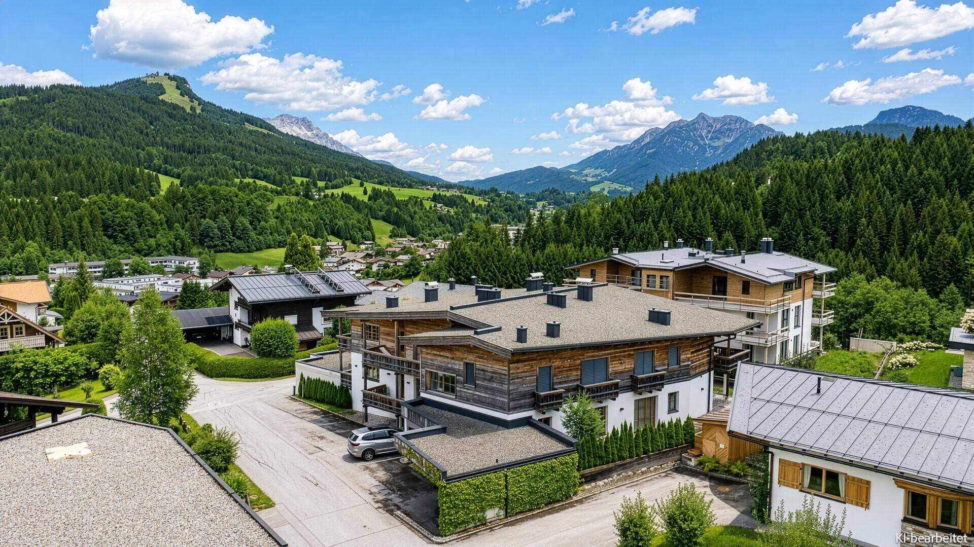 Wohngebäude in alpiner Landschaft mit Holzelementen und Bergblick unter blauem Himmel.
