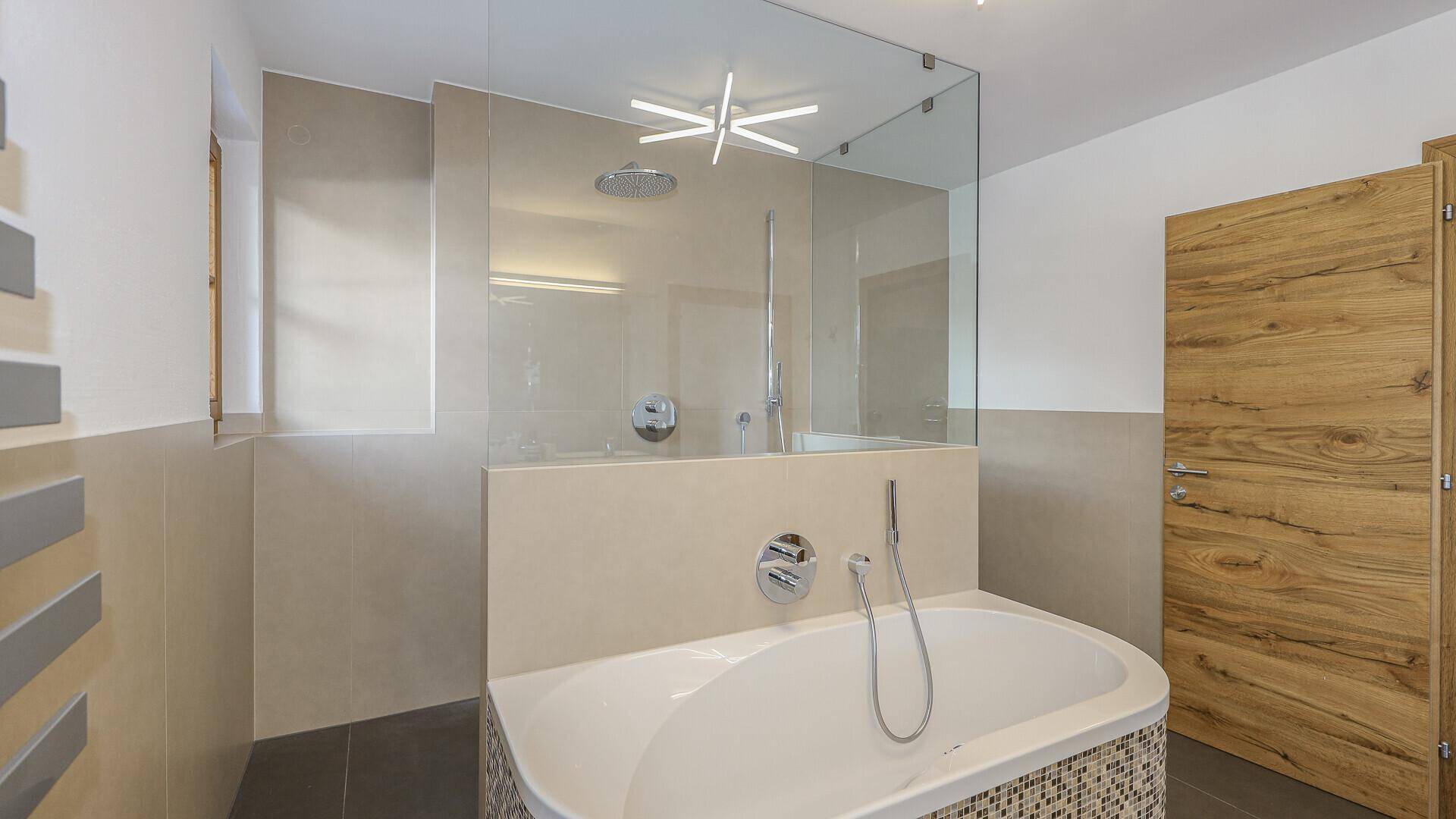 Elegantes Badezimmer mit Badewanne, großer Dusche und modernen Armaturen.