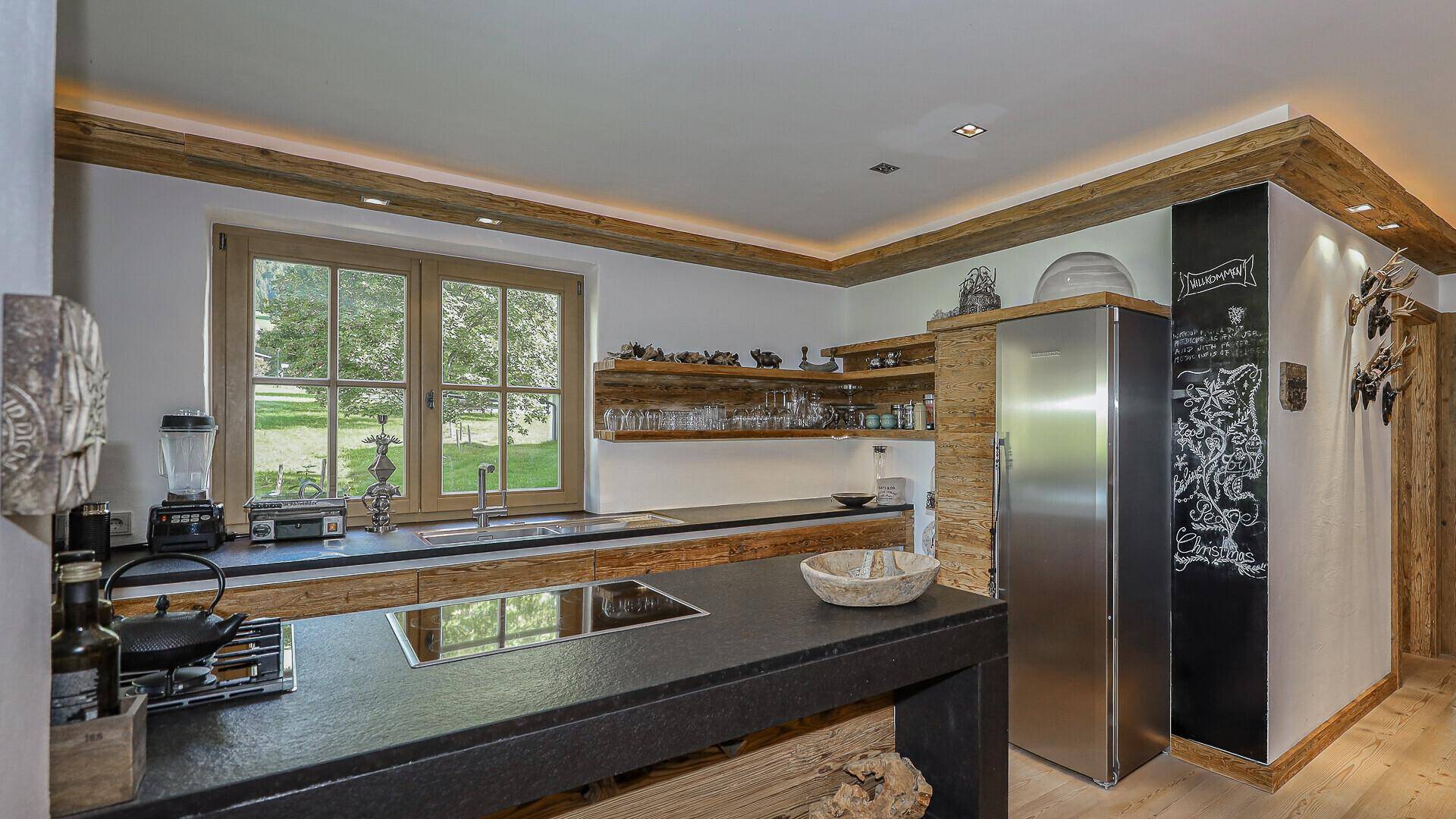 Funktionale Küche mit integriertem Kühlschrank, Kochinsel und Kreidetafel an der Wand.