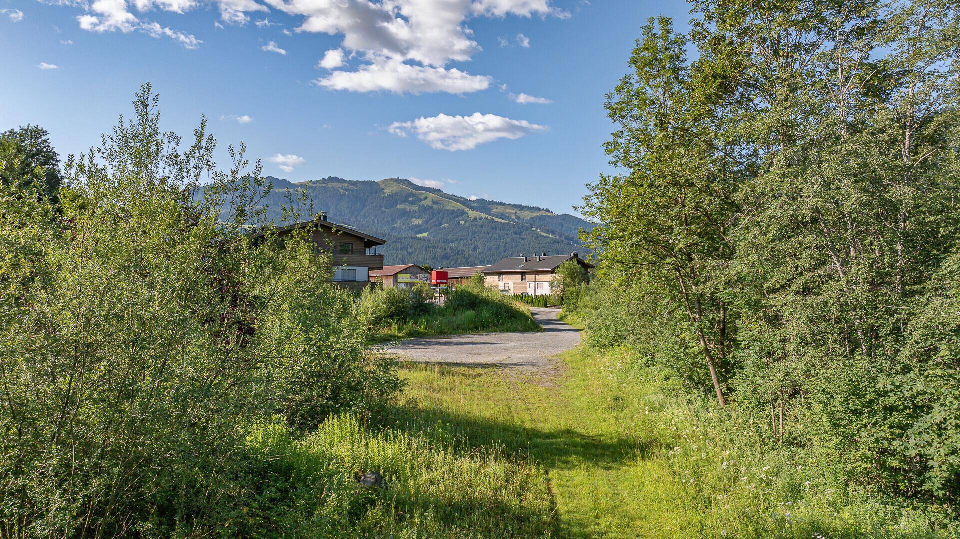 Blick vom Grundstück auf die umliegende Bebauung und die sanften grünen Hügel im Hintergrund.