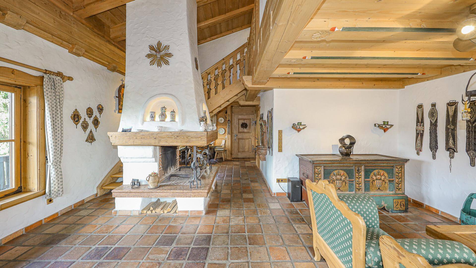 Geräumiges Wohnzimmer im alpinen Stil mit Kamin, Holzbalken und traditionellen Möbeln.