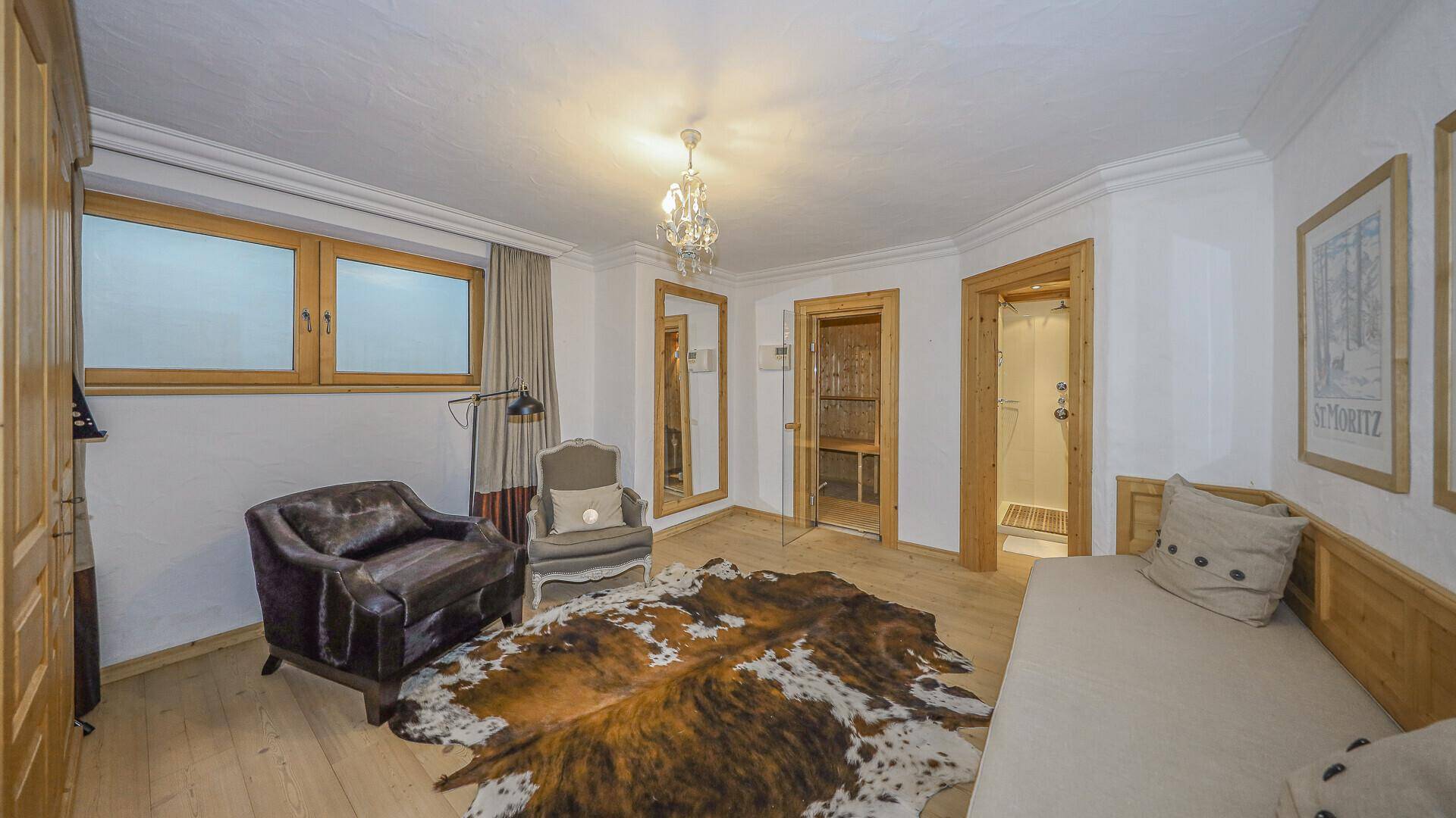 Schlafzimmer mit Tagesbett, großem Spiegel und direktem Zugang zu Sauna und Dusche.