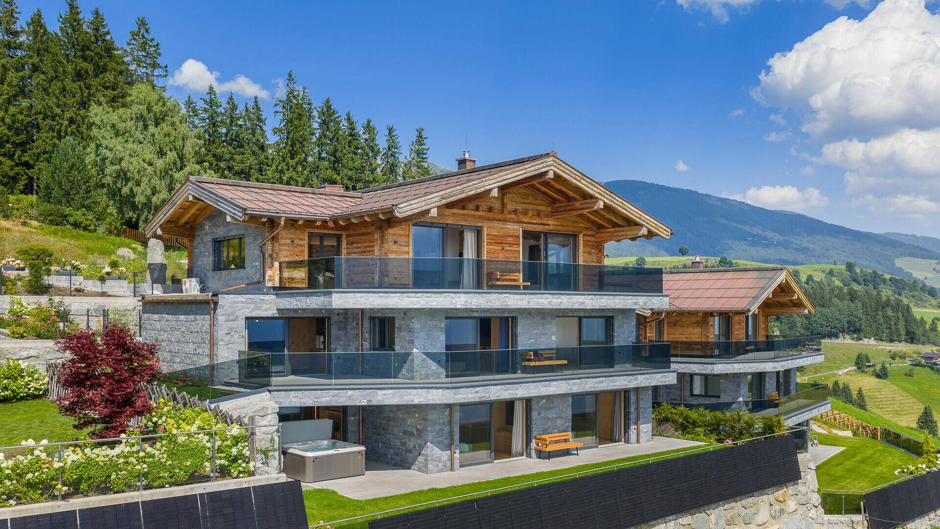Luxuriöses Chalet mit moderner Architektur, Stein- und Holzfassade, umgeben von alpiner Landschaft.