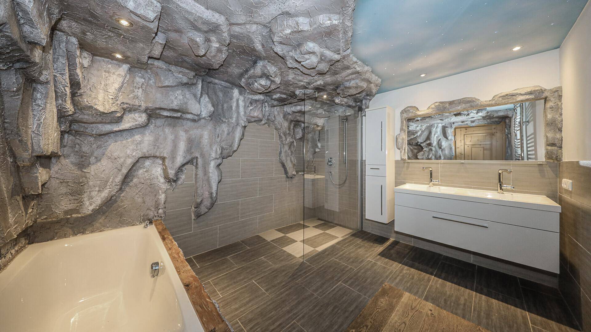 Außergewöhnliches Badezimmer mit Felswand-Design, Badewanne, Dusche und Doppelwaschbecken.