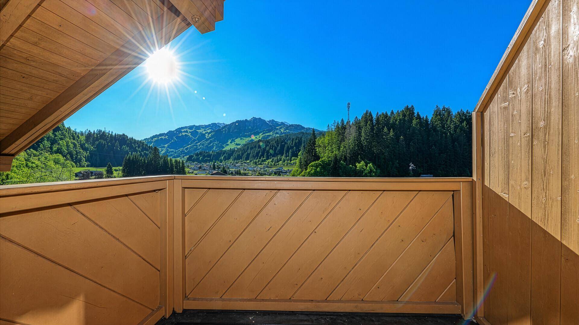 Sonnige Loggia mit Holzboden und atemberaubendem Blick auf die umliegende Berglandschaft.