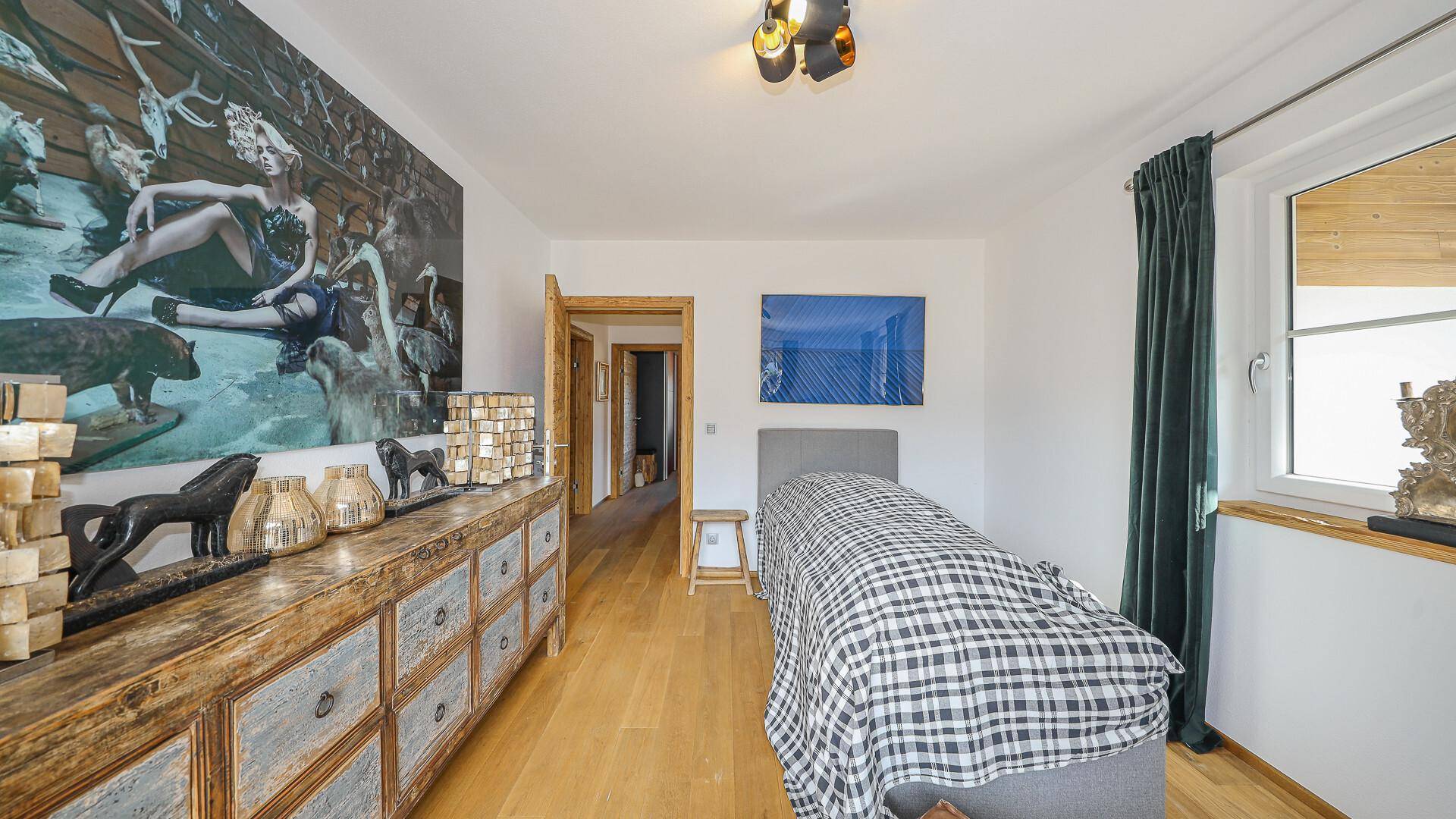 Schlafzimmer mit Einzelbett, Kommode und großem Wandbild, bietet viel Platz.