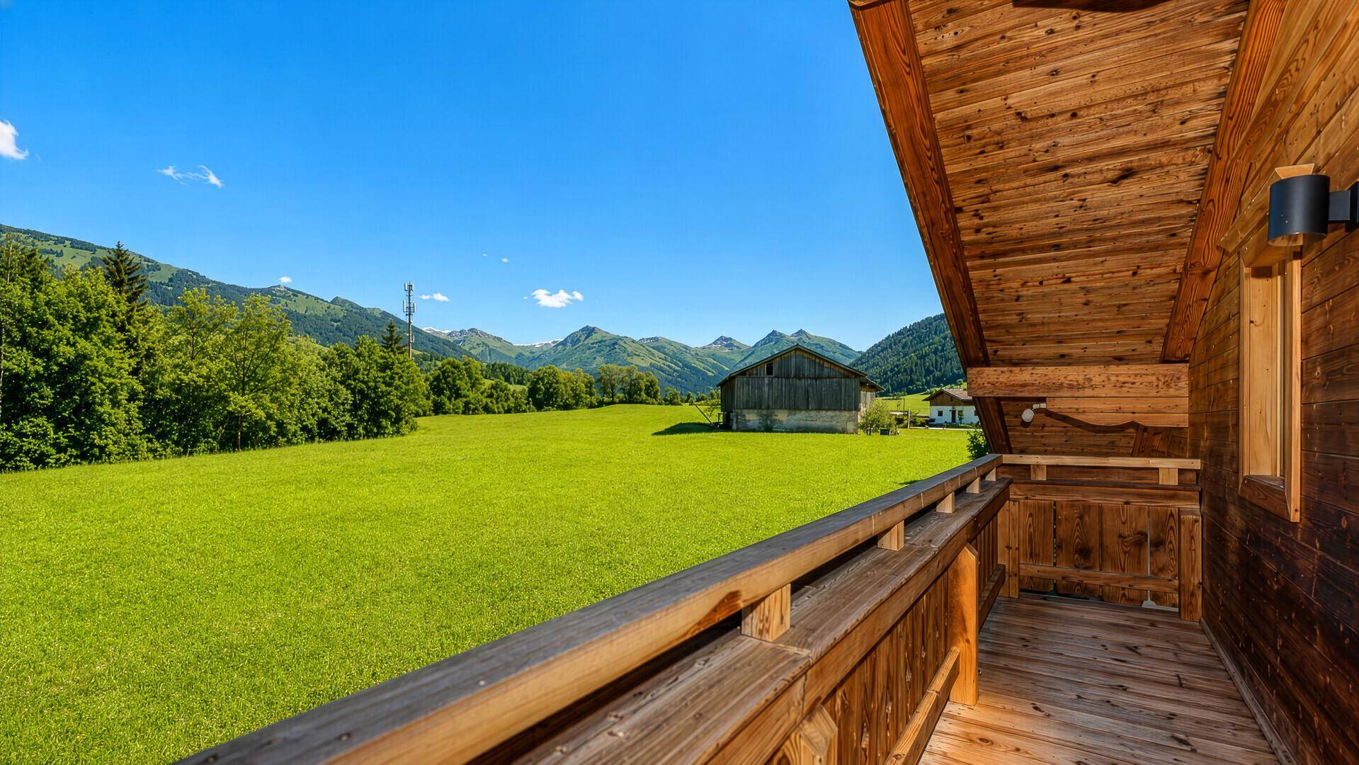Holzbalkon mit weitem Blick über grüne Wiesen und majestätische Berge.