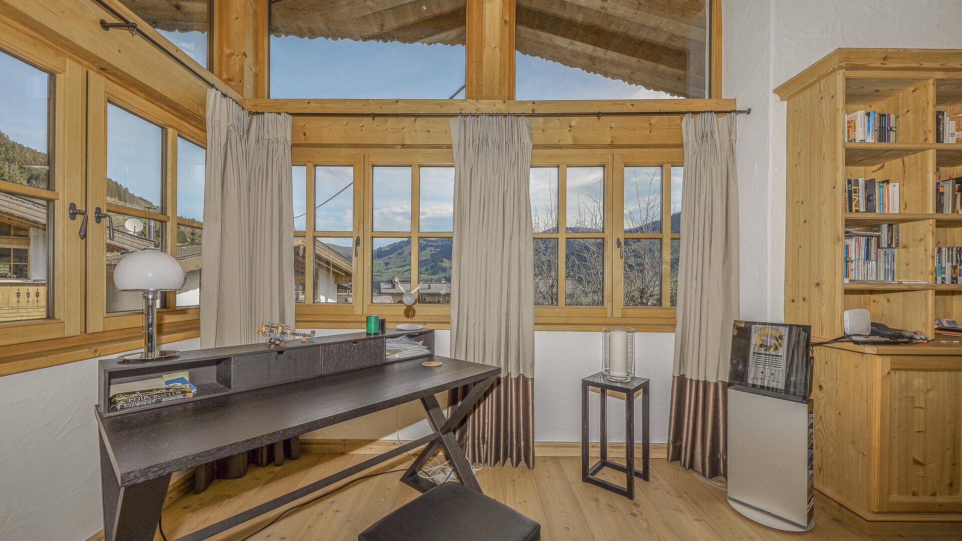 Arbeitsbereich mit Bergblick, großen Fenstern und Holzboden im alpinen Stil.
