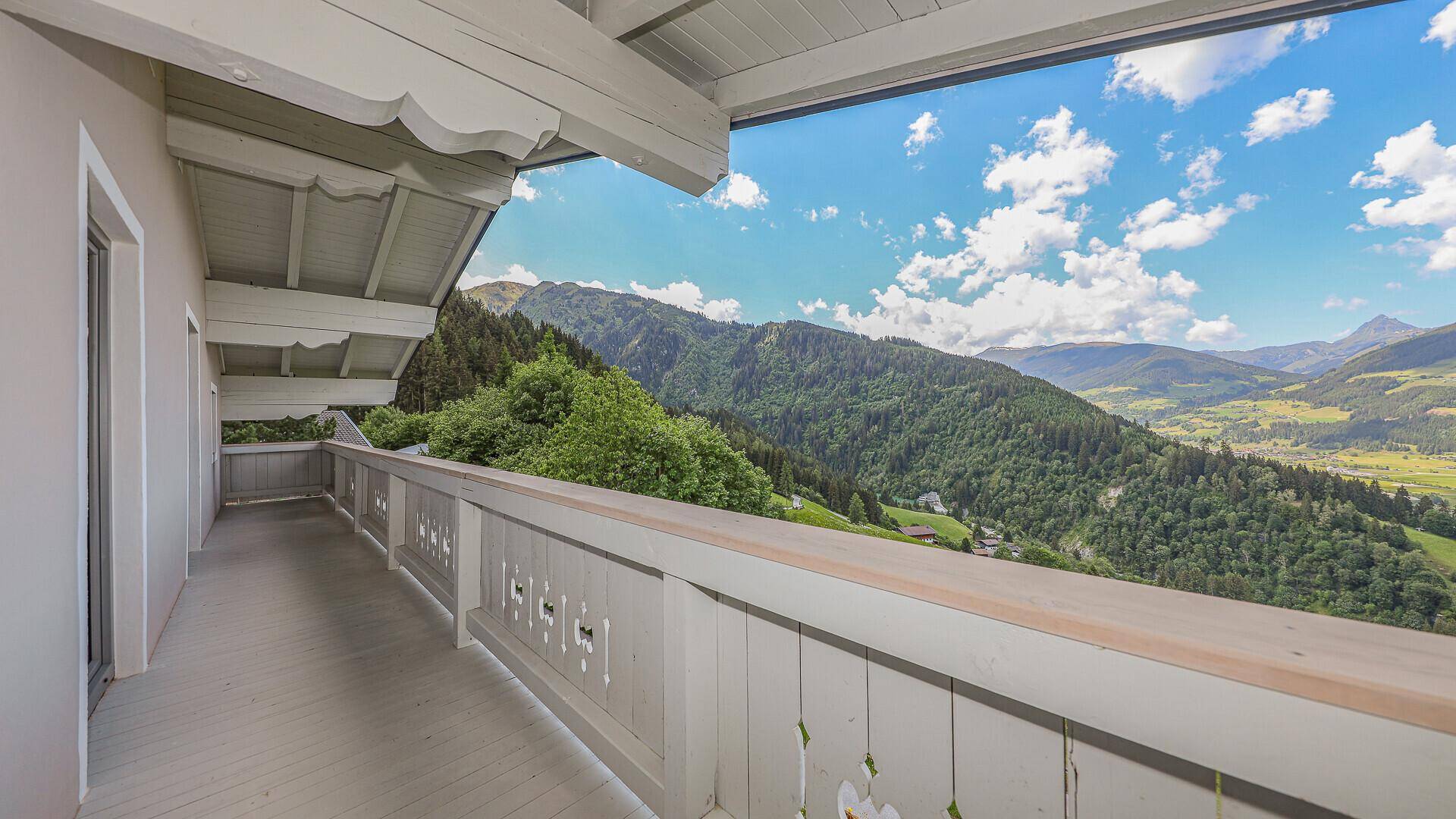 Geräumiger Balkon mit traditionellem Holzgeländer und Panoramablick auf die umliegende Bergwelt.