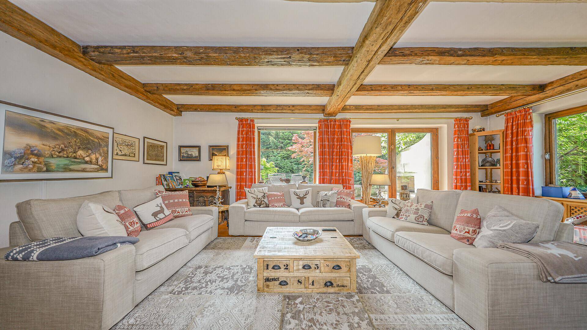 Gemütliches Wohnzimmer im alpinen Stil mit bequemen Sofas und Blick ins Grüne.