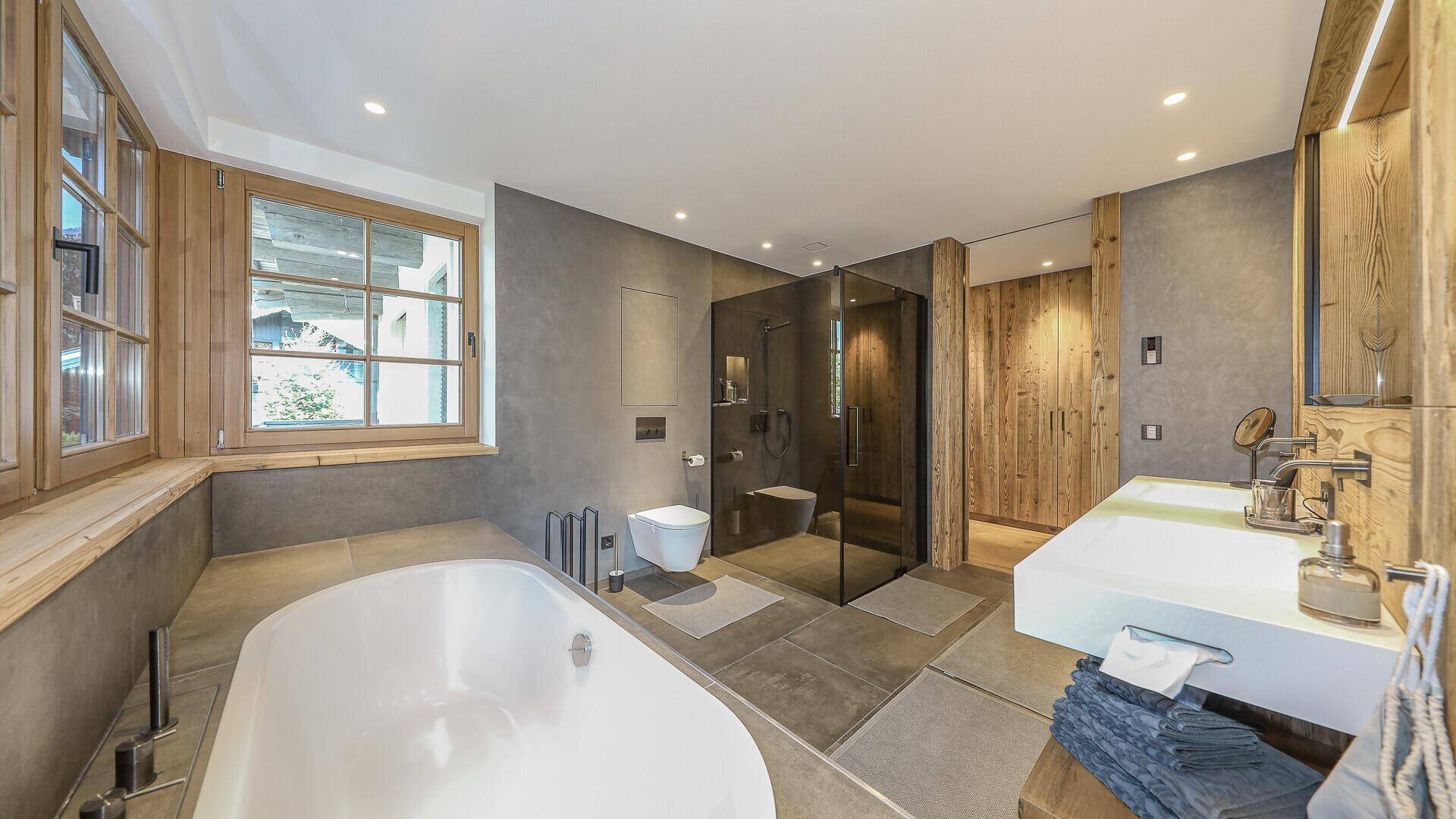 Modernes Badezimmer mit Badewanne, begehbarer Dusche, Doppelwaschbecken und Holzakzenten.