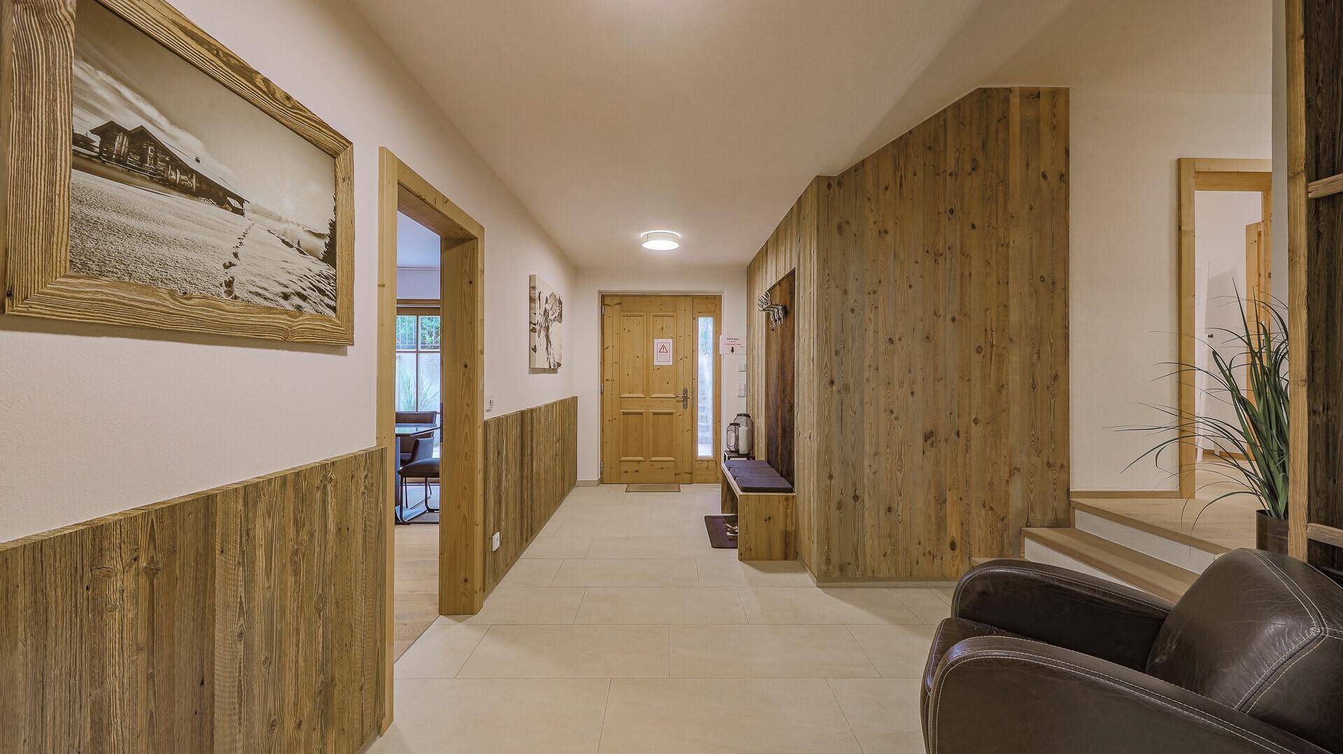 Heller Eingangsbereich mit Holzvertäfelung, Garderobe und Zugang zu den Wohnräumen.