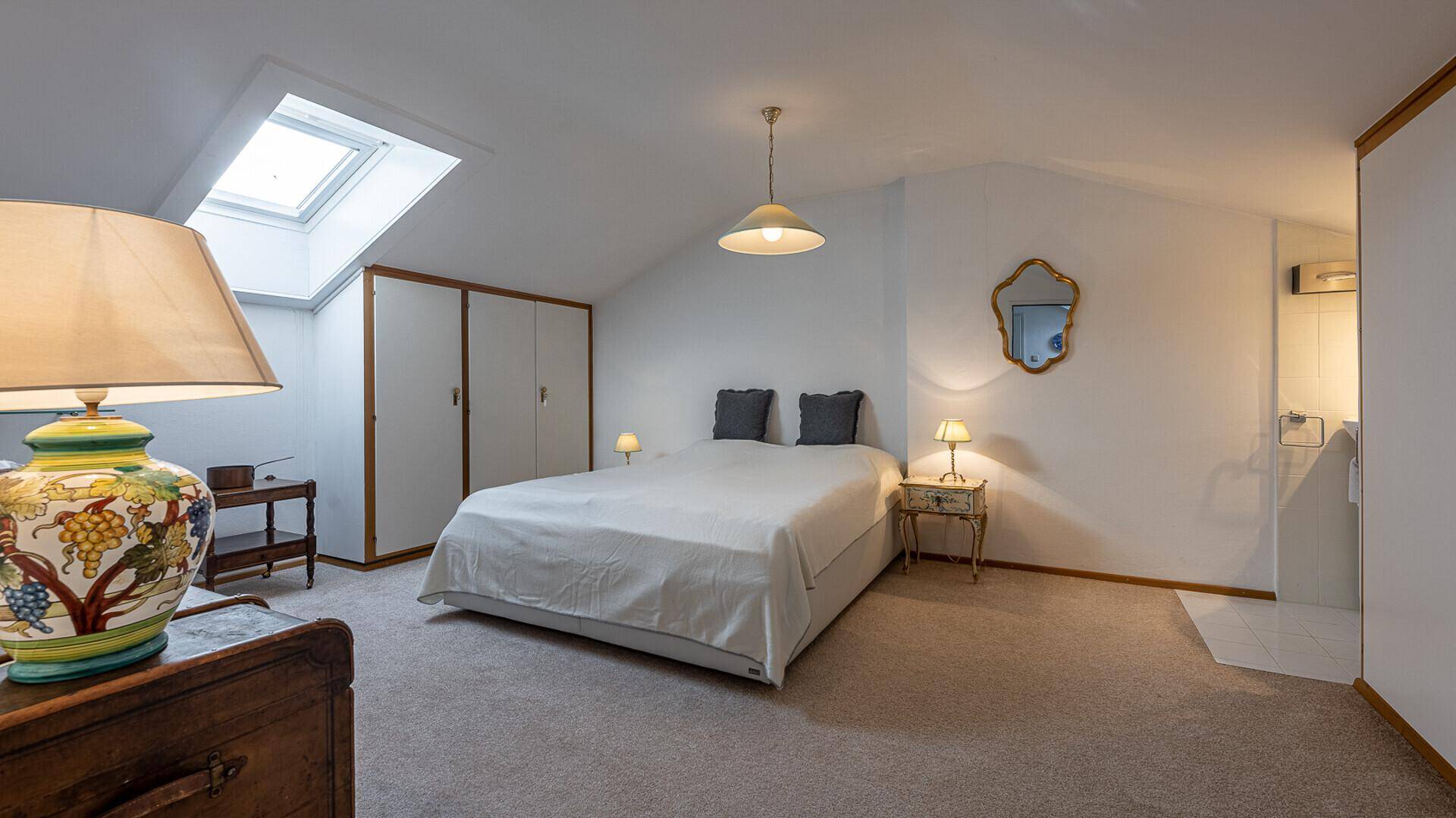Helles Dachgeschoss-Schlafzimmer mit Doppelbett, Einbauschränken und Dachfenster für viel Tageslicht.