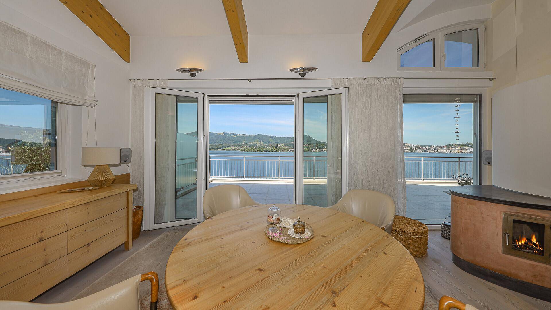 Essbereich mit Holztisch, bequemen Stühlen und direktem Zugang zur Terrasse mit Seeblick.