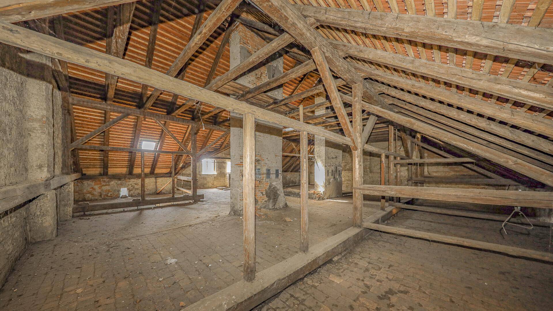 Geräumiger Dachboden mit freiliegenden Holzbalken und Ziegelboden, bietet Ausbaupotenzial.