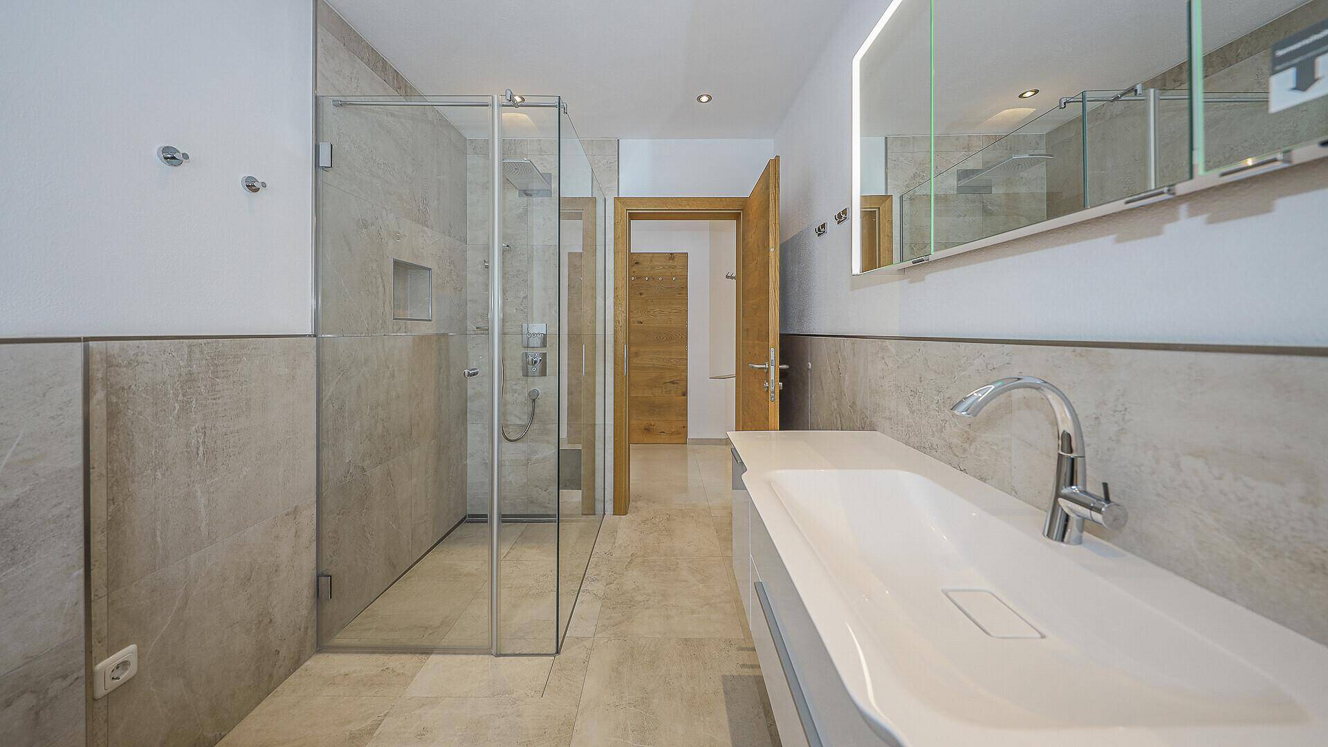 Modernes Badezimmer mit begehbarer Dusche, großem Waschtisch und Spiegelschrank.