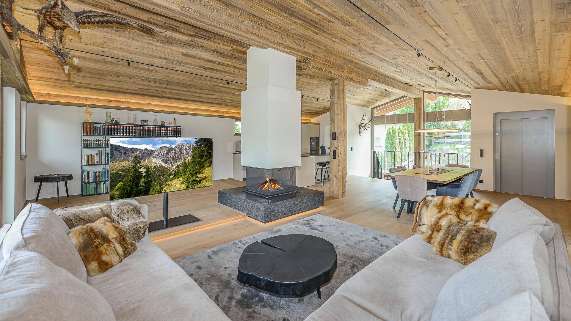 Großzügiger offener Wohnbereich mit Kamin, Holzbalkendecke und gemütlichen Sitzgelegenheiten.