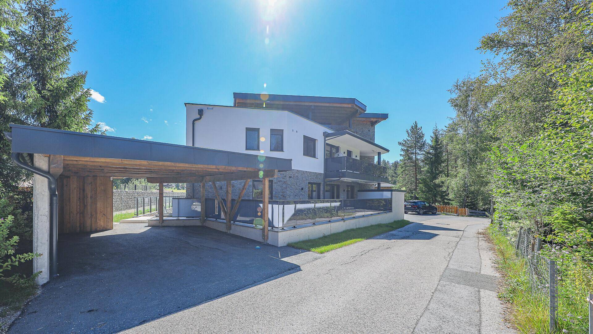 Außenansicht des modernen Gebäudes mit Carport und umgebender Natur.