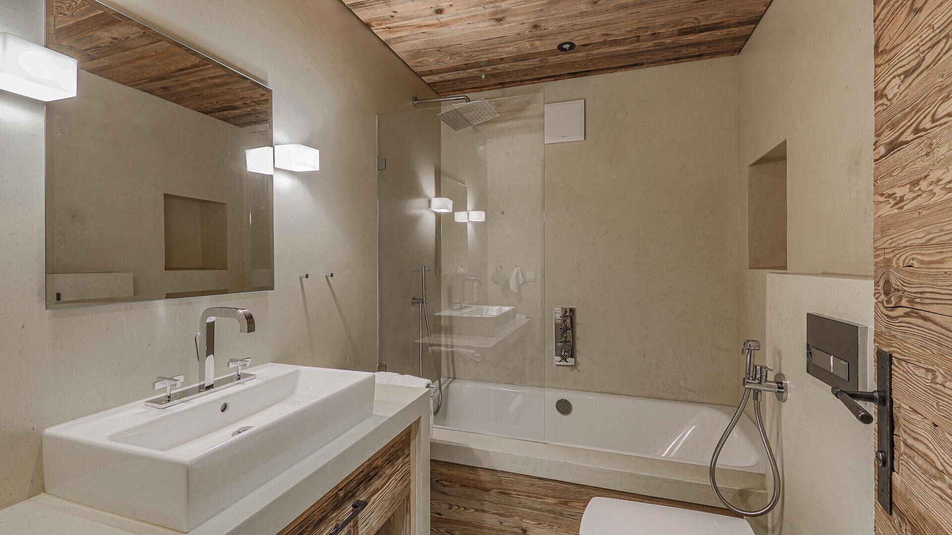 Modernes Badezimmer mit Badewanne, Dusche, Einzelwaschbecken und Holzdecke.