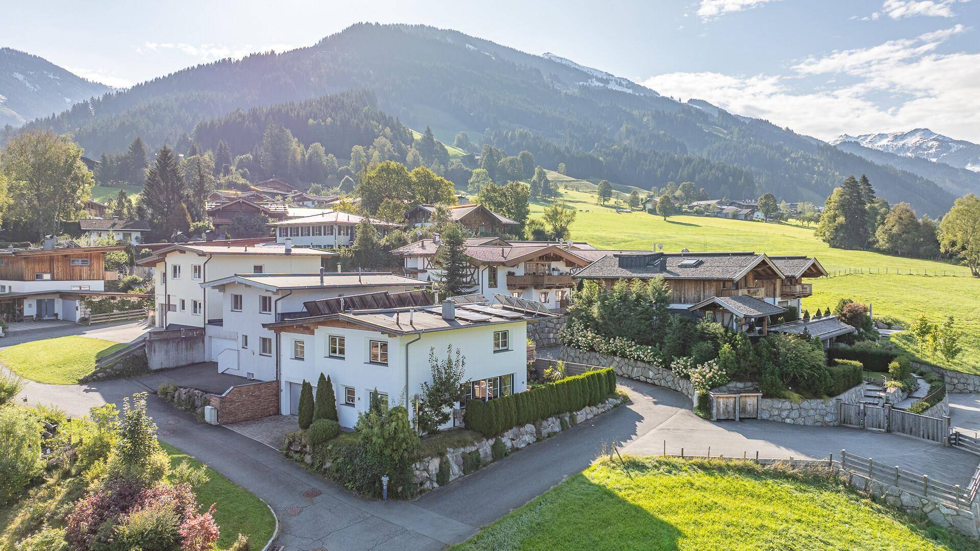 Malerische Wohngegend in den Bergen mit grünen Wiesen und traditionellen Häusern.
