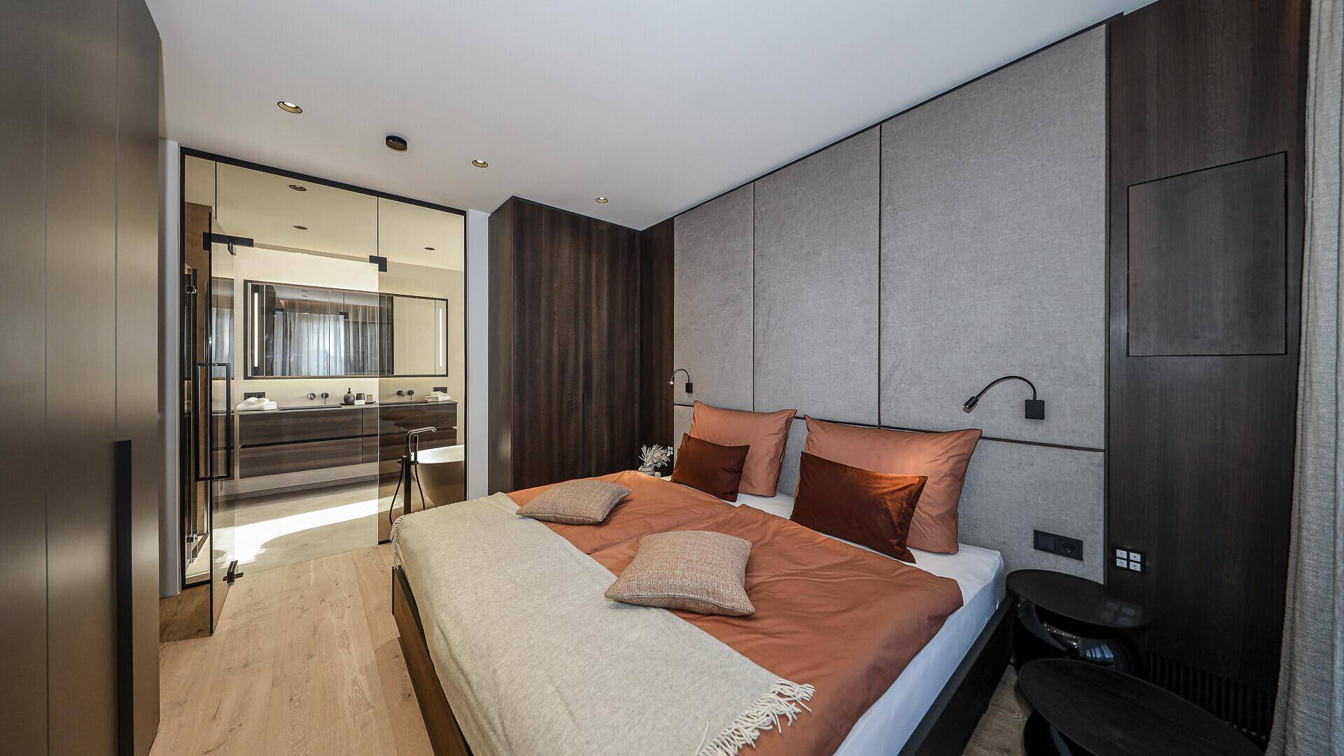 Modernes Schlafzimmer mit Holzboden und direktem Zugang zu einem stilvollen Badezimmer.