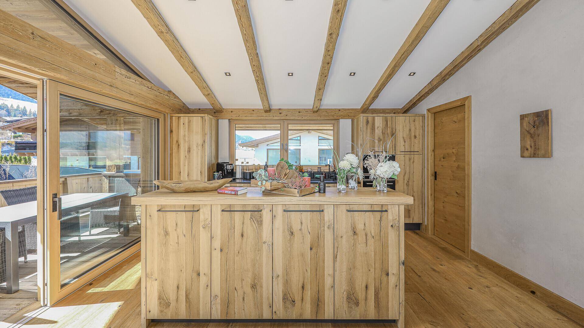 Moderne Holzküche mit Kücheninsel und direktem Zugang zu einer Außenterrasse.