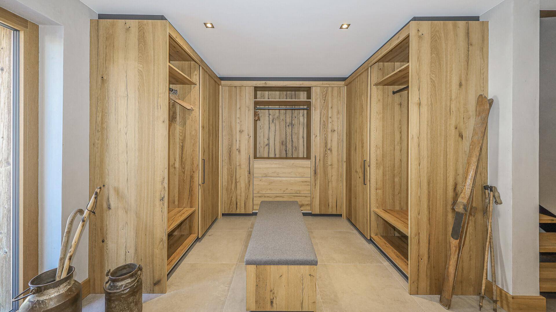 Großer begehbarer Kleiderschrank mit maßgefertigten Holzschränken und Sitzbank.