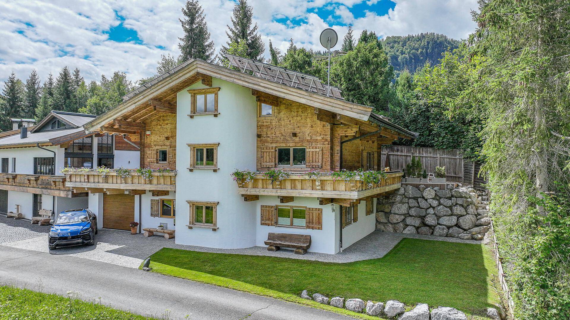 Großzügiges Chalet-Haus mit Holzfassade, Balkonen und umgebender Natur.