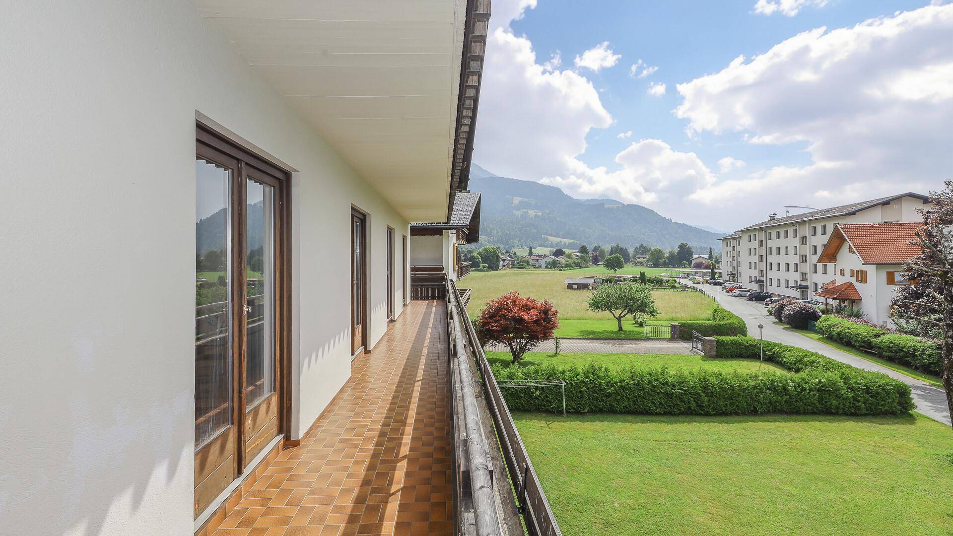 Geräumiger Balkon mit traditionellem Holzgeländer und Fliesenboden, ideal zum Entspannen mit Bergblick.