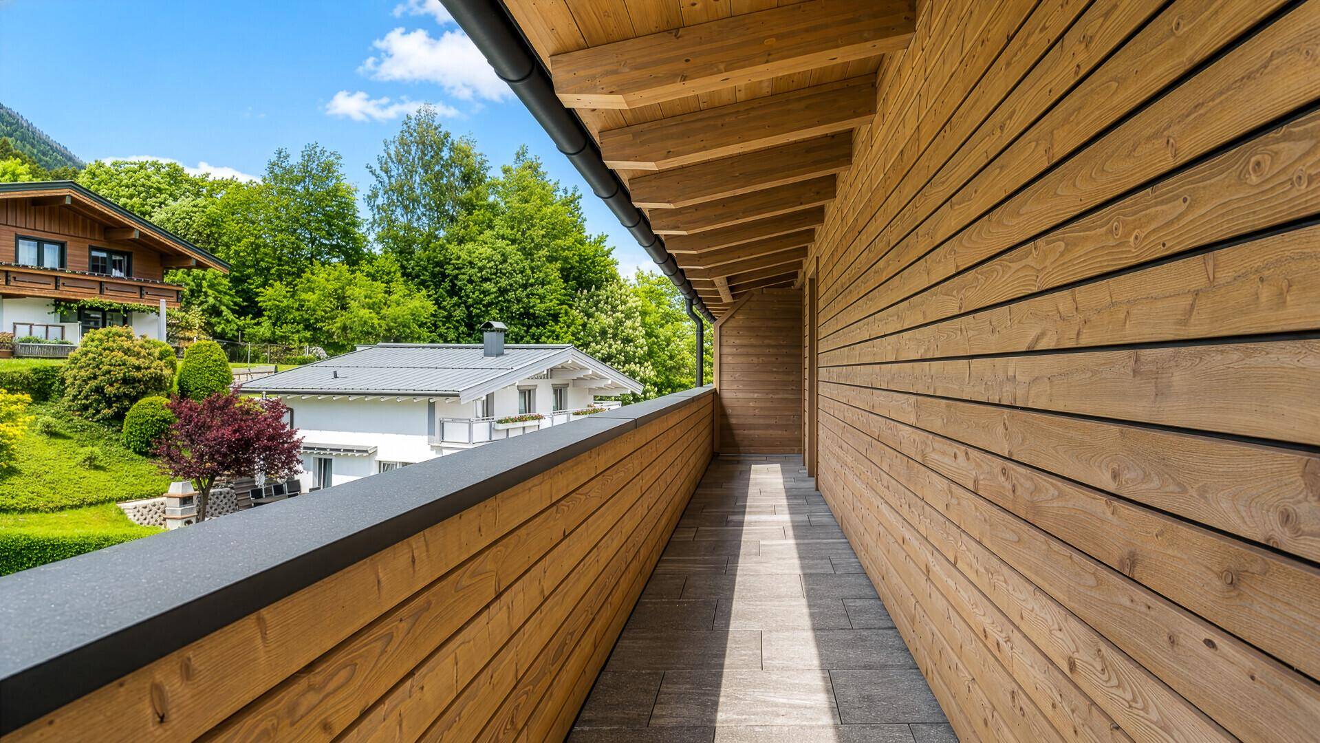 Langer, schmaler Balkon mit Holzverkleidung und Blick auf die umliegende Wohngegend.