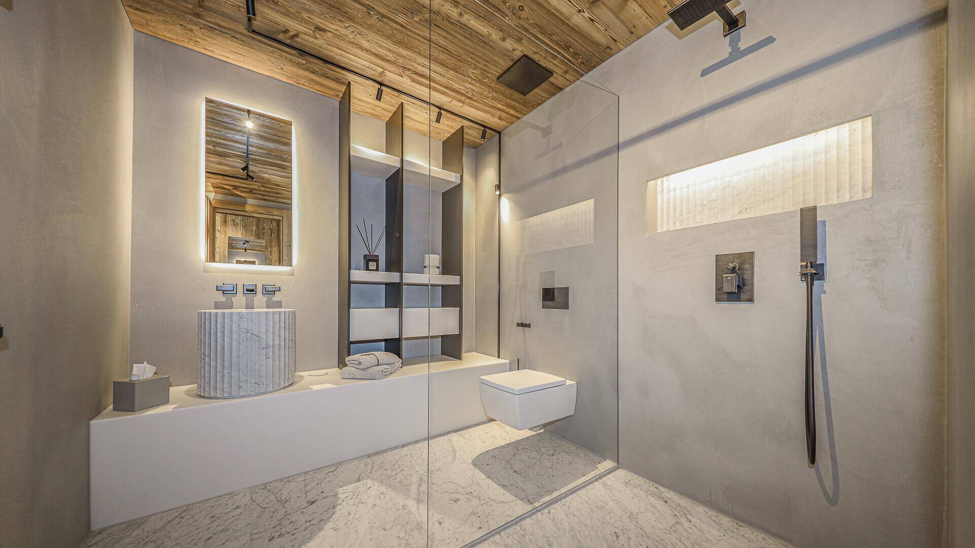 Modernes Badezimmer mit begehbarer Dusche, beleuchtetem Spiegel und stilvollem Waschbecken.