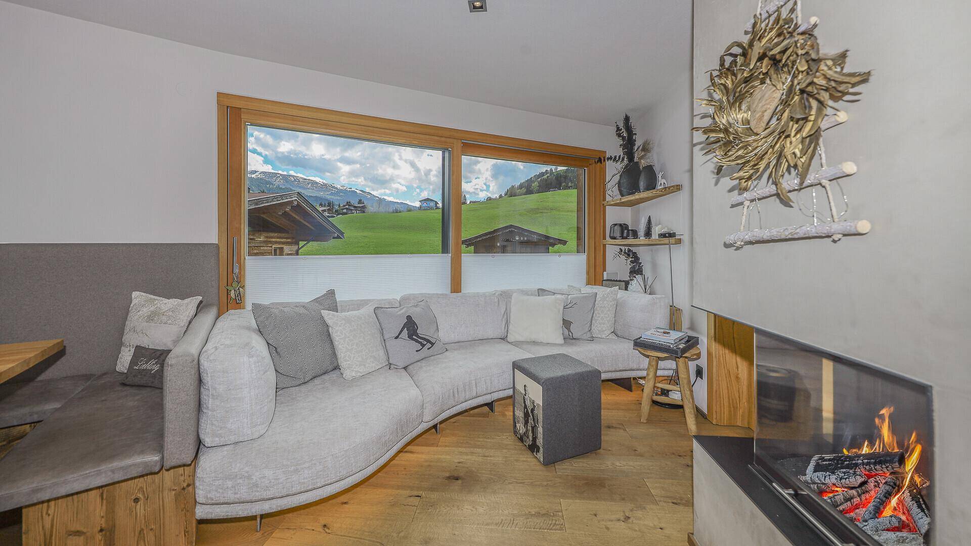 Heller Wohnbereich mit Kamin und weitem Blick auf die umliegende Berglandschaft.