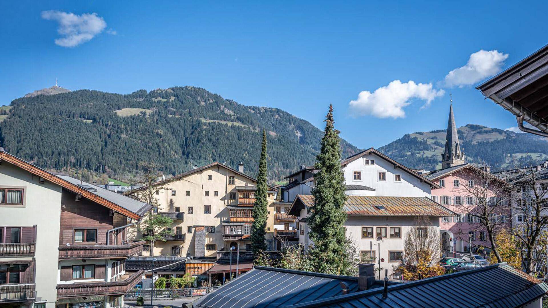 Panoramablick auf ein malerisches Dorf mit traditionellen Häusern und majestätischen Bergen im Hintergrund.