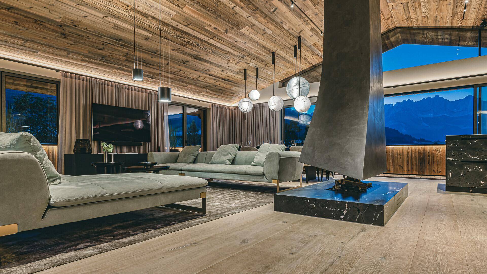 Geräumiges Wohnzimmer mit Holzbalkendecke, modernem Kamin und Bergblick.