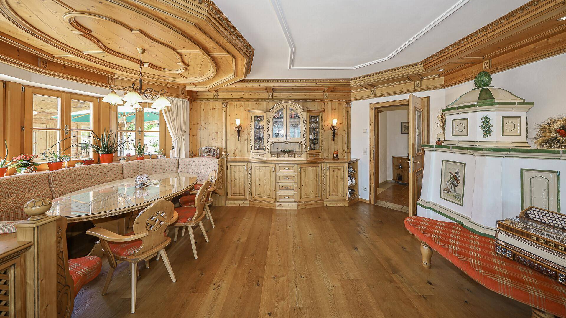 Alpenländischer Essbereich mit Holztisch, Kachelofen und traditionellen Möbeln.