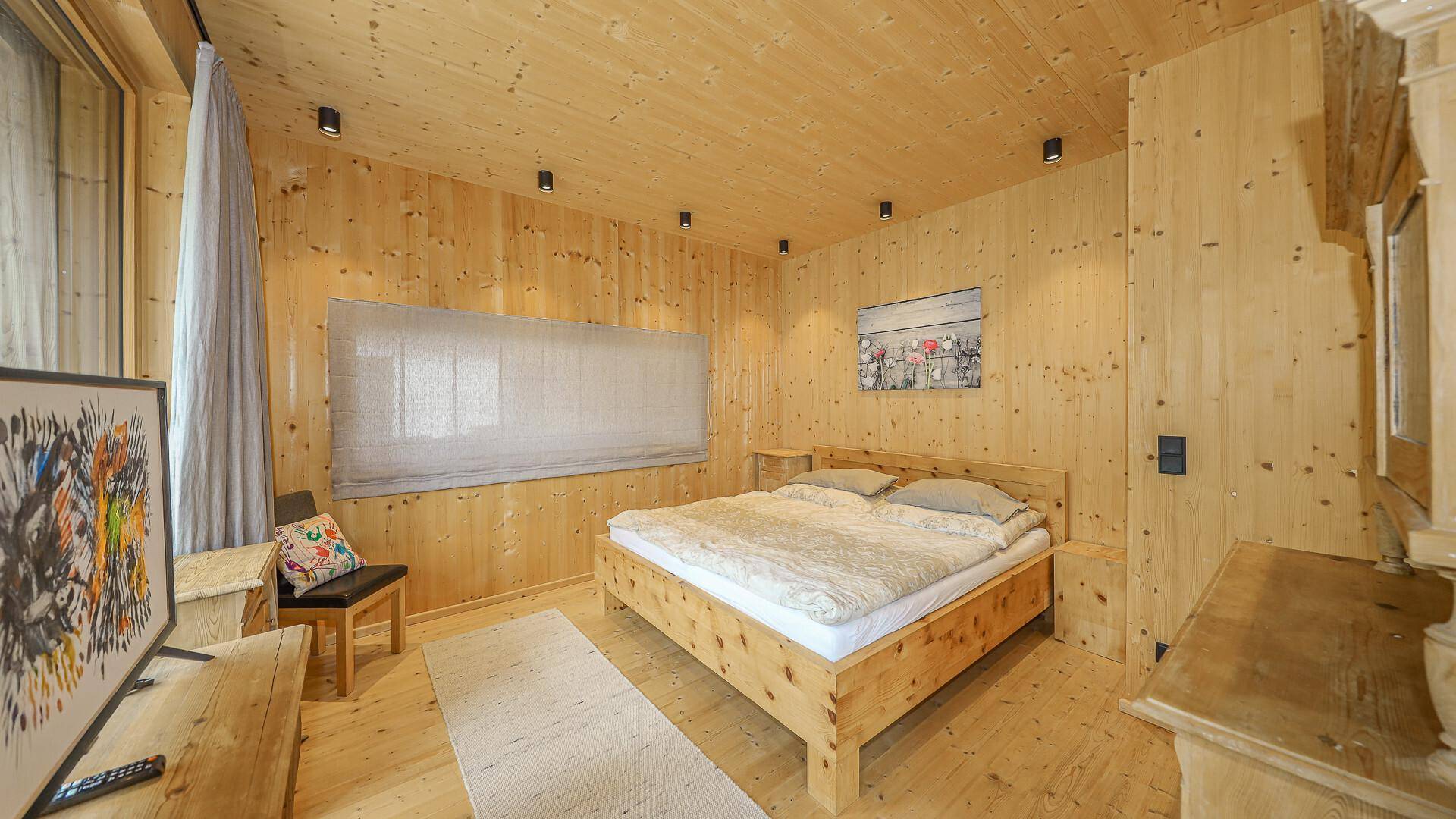Gemütliches Schlafzimmer mit Holzwänden, Holzboden und einem großen Doppelbett.