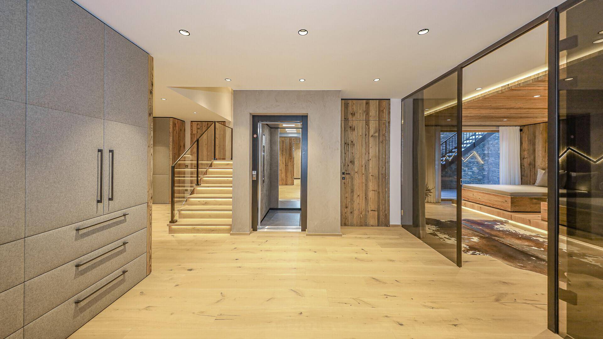 Heller Eingangsbereich mit Aufzug, Treppe und Einbauschränken im modernen Design.