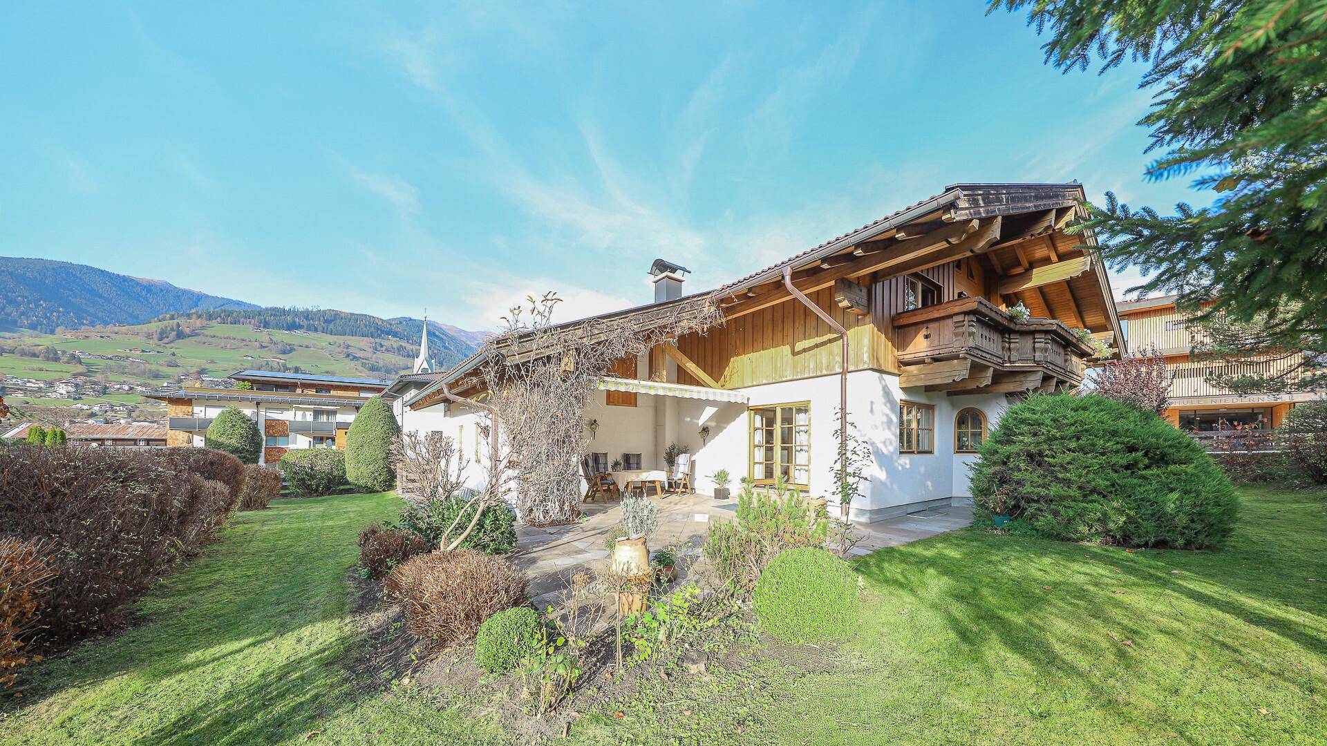 Gepflegter Gartenbereich mit Rasen, Sträuchern und der Rückseite des Hauses.