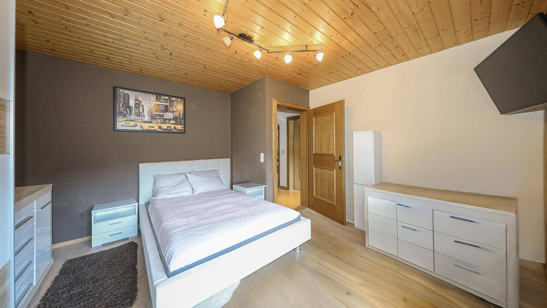 Modern eingerichtetes Schlafzimmer mit Holzboden und schlichter Farbgestaltung.