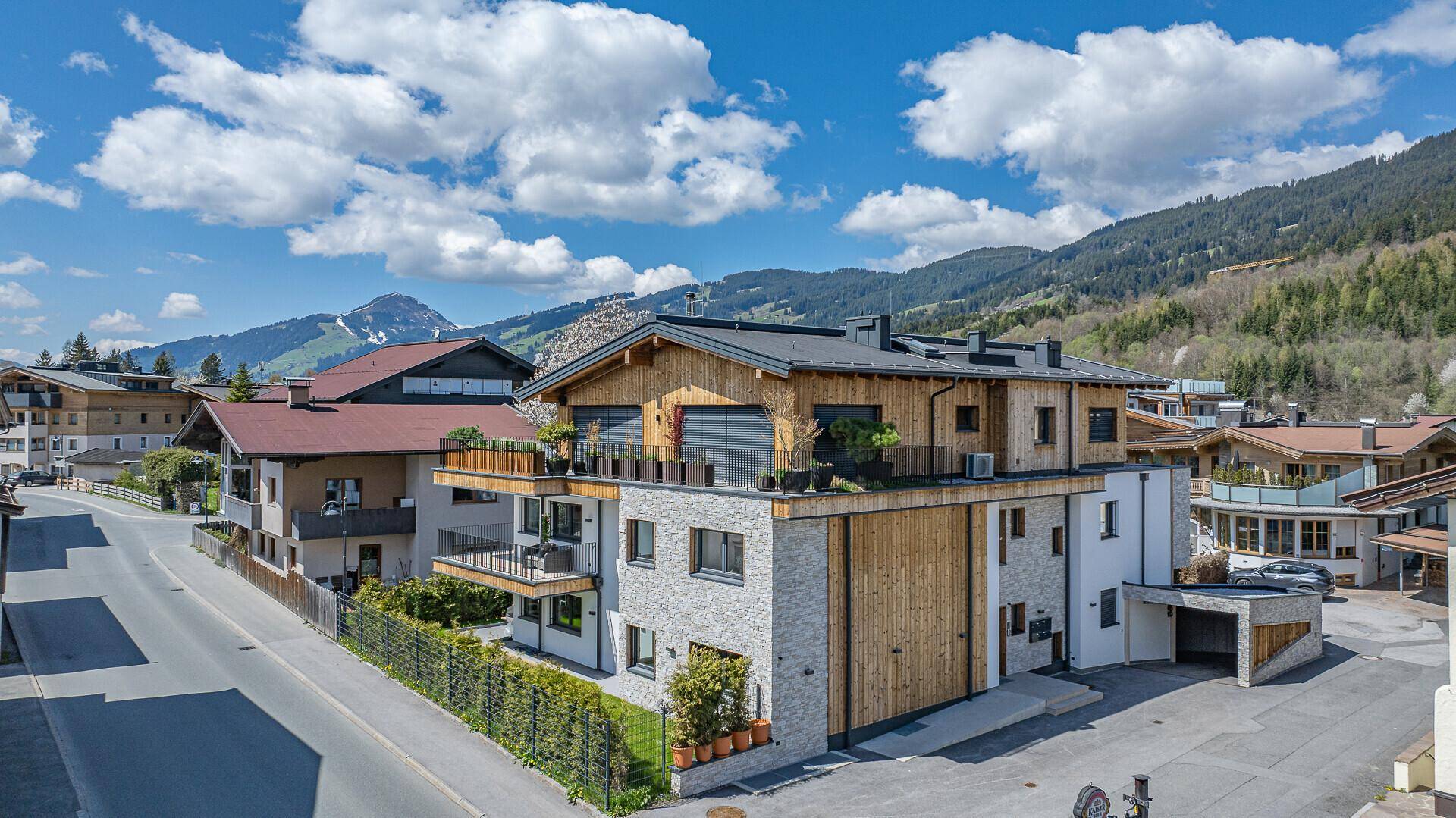 Modernes Wohngebäude mit Holz- und Steinfassade in einer malerischen Berglandschaft.